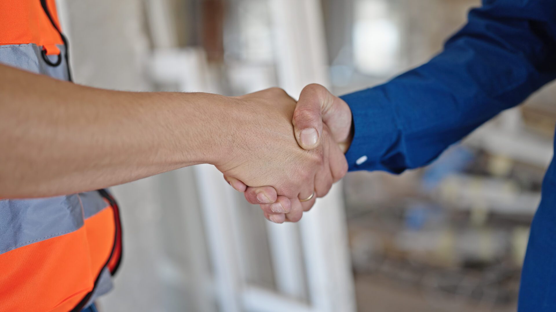 Two men builder and architect shake hands at construction site A close up of two men shaking their hands